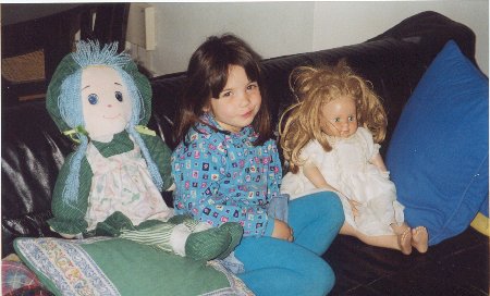 Girl in the sofa with two dolls
